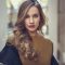 Beautiful blonde russian woman in urban background Blonde woman in urban background. Beautiful young girl wearing black leather jacket and mini skirt standing in the street. Pretty russian female with long wavy hair hairstyle and blue eyes.